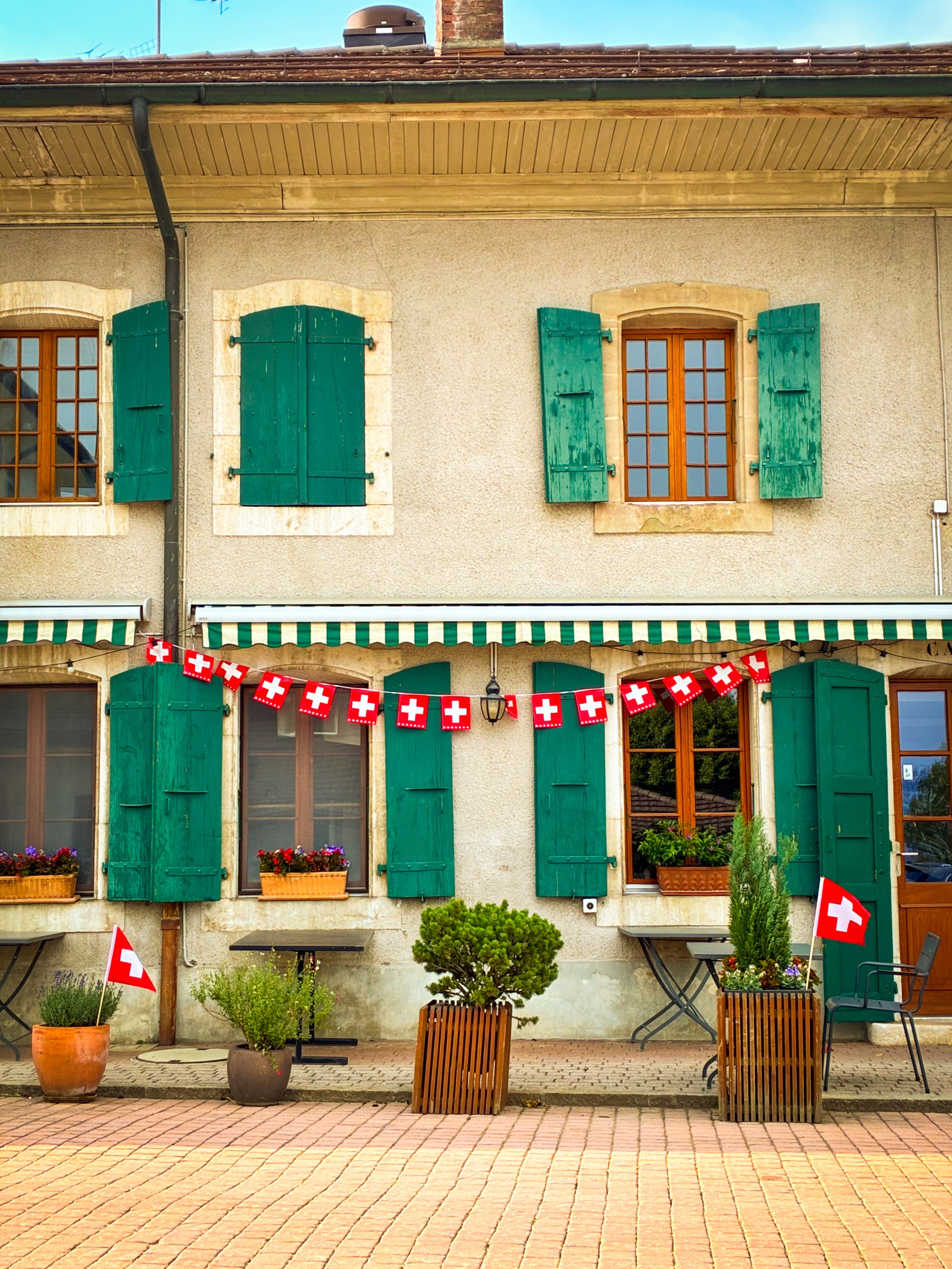 Façade de l’Auberge Au Sapin décorée avec des drapeaux suisses